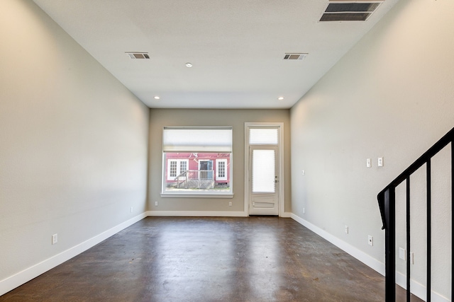 foyer entrance with finished concrete flooring, visible vents, and baseboards