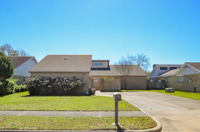 view of front of home with brick siding, driveway, a shingled roof, and a front lawn