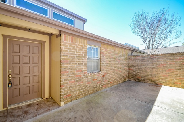 entrance to property with a patio area and brick siding