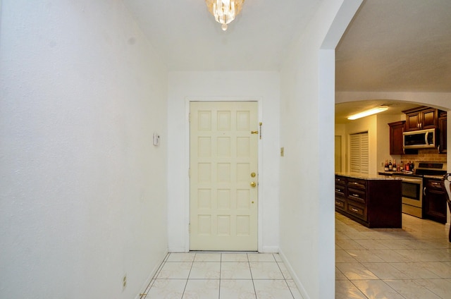 entrance foyer featuring arched walkways, baseboards, and light tile patterned flooring