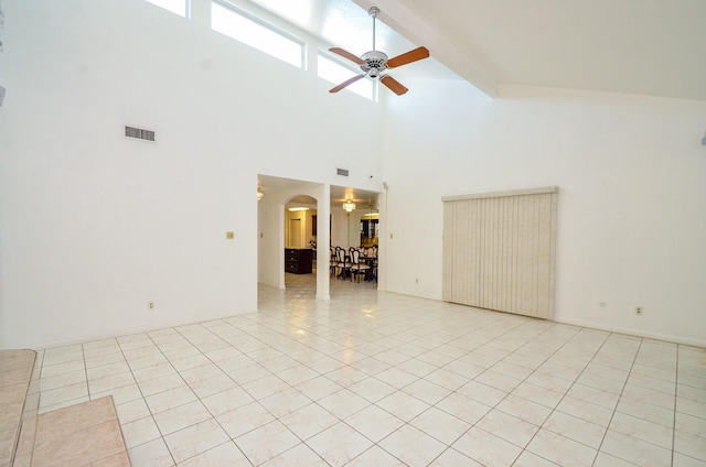 empty room with light tile patterned floors, visible vents, arched walkways, and ceiling fan