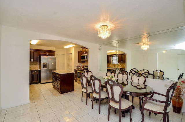 dining room featuring light tile patterned floors and arched walkways