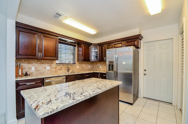 kitchen featuring visible vents, backsplash, appliances with stainless steel finishes, light tile patterned flooring, and a sink