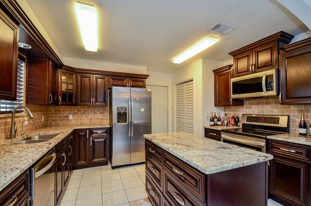 kitchen with tasteful backsplash, visible vents, light stone countertops, appliances with stainless steel finishes, and a sink