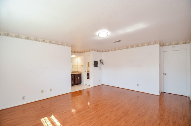 spare room featuring light wood-style flooring, baseboards, and visible vents