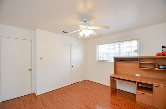 interior space featuring light wood finished floors, visible vents, a ceiling fan, and baseboards