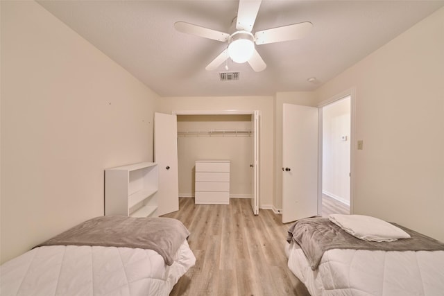 bedroom featuring light wood finished floors, visible vents, baseboards, a closet, and a ceiling fan