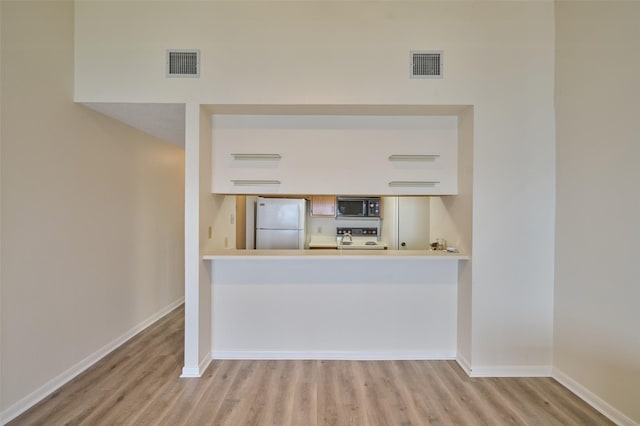 kitchen with visible vents, range, black microwave, and freestanding refrigerator