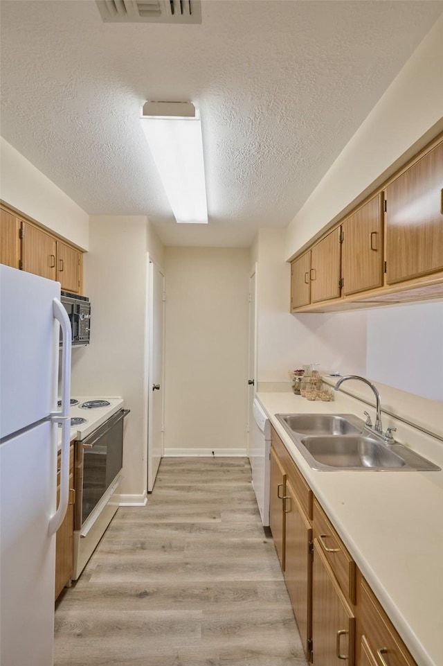 kitchen featuring white appliances, visible vents, a sink, light countertops, and light wood-style floors