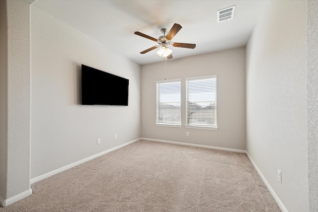 carpeted spare room featuring visible vents, baseboards, and ceiling fan