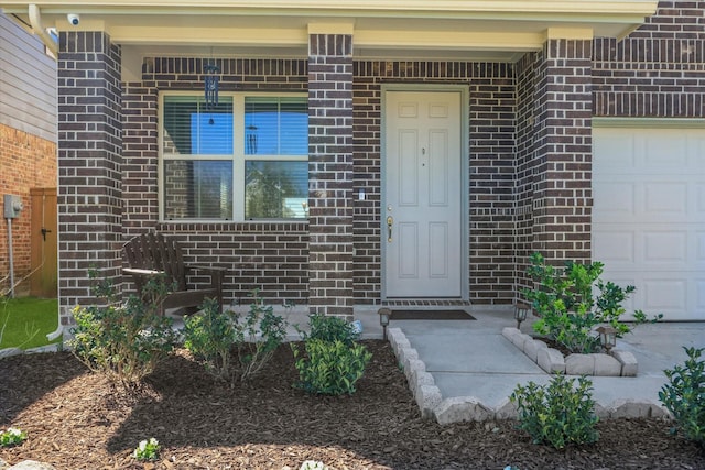 entrance to property featuring a garage and brick siding