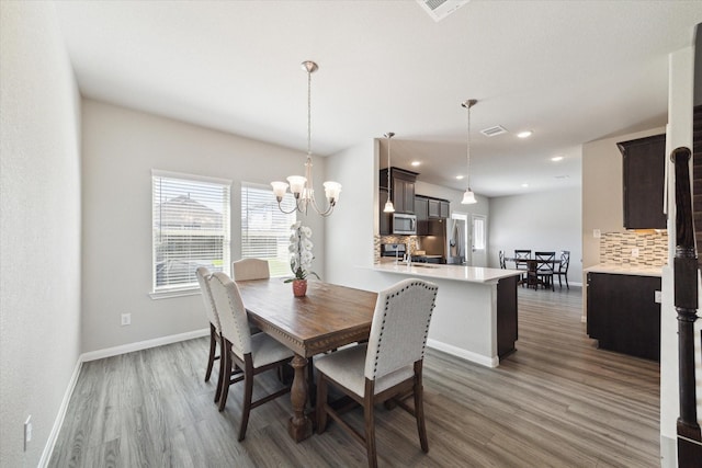 dining area featuring visible vents, an inviting chandelier, baseboards, and wood finished floors