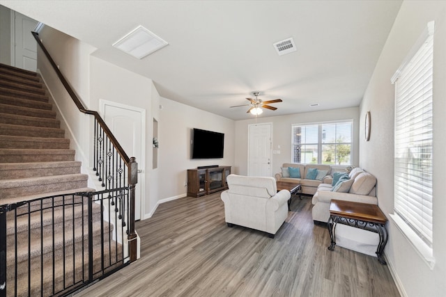 living area featuring visible vents, stairway, a ceiling fan, and wood finished floors