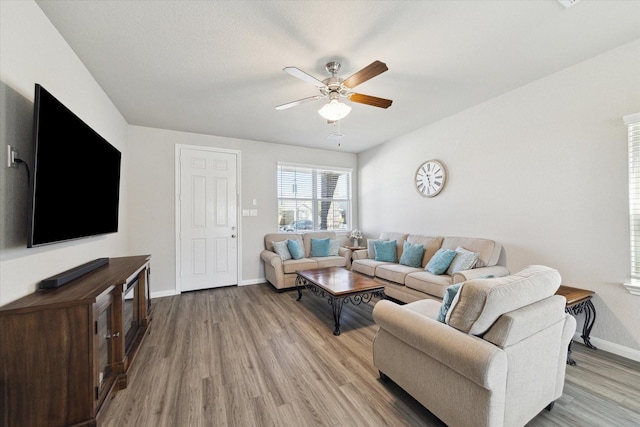 living area with light wood-type flooring, baseboards, and a ceiling fan