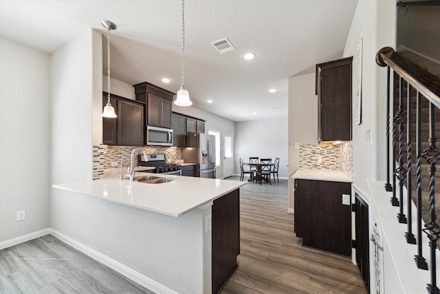 kitchen with wood finished floors, visible vents, a sink, dark brown cabinets, and appliances with stainless steel finishes