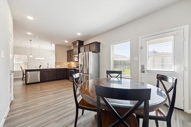 dining room featuring baseboards, plenty of natural light, and light wood-style floors