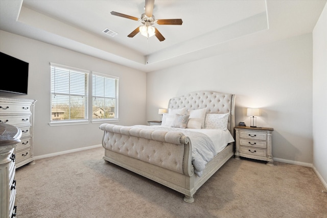 bedroom with baseboards, visible vents, ceiling fan, light carpet, and a raised ceiling