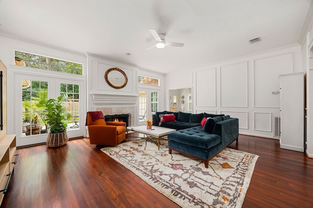 living room featuring plenty of natural light, ceiling fan, a fireplace, and a decorative wall