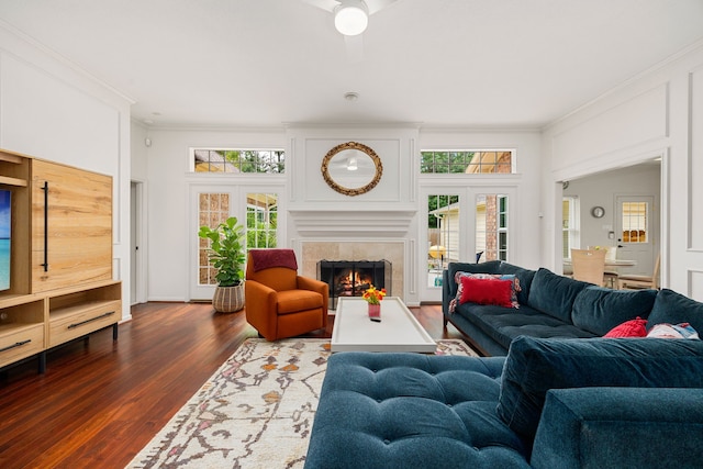 living area featuring dark wood-style floors, a healthy amount of sunlight, a high end fireplace, and ornamental molding