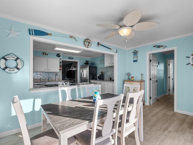 dining space with a ceiling fan, light wood-style floors, baseboards, and ornamental molding