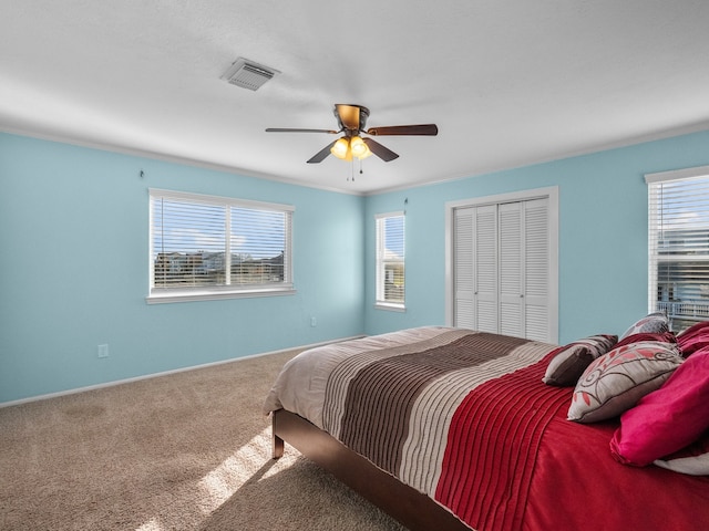 bedroom with a ceiling fan, carpet, visible vents, ornamental molding, and a closet