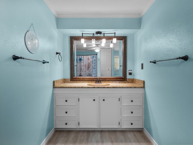 bathroom with ornamental molding, wood finished floors, a shower with shower curtain, baseboards, and vanity