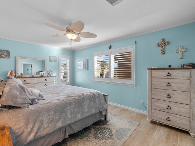 bedroom with visible vents, ornamental molding, wood finished floors, baseboards, and ceiling fan