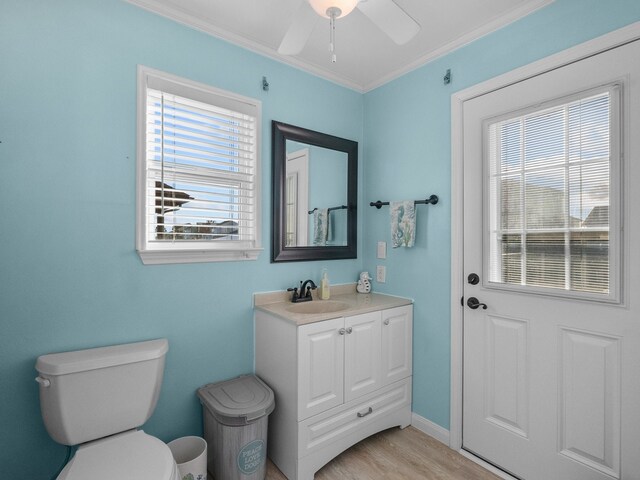 bathroom with toilet, a ceiling fan, wood finished floors, crown molding, and vanity