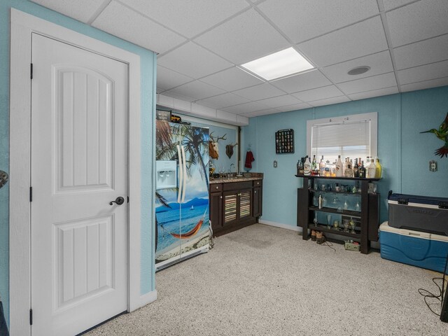 miscellaneous room with a sink, a drop ceiling, and baseboards