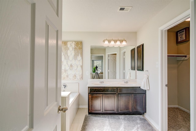 full bathroom featuring baseboards, visible vents, double vanity, a sink, and a bath