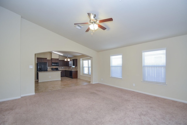 unfurnished living room with light carpet, arched walkways, ceiling fan, and vaulted ceiling