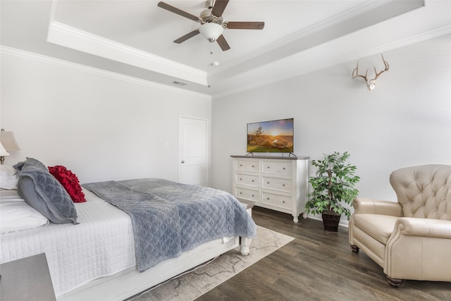 bedroom with visible vents, a raised ceiling, wood finished floors, and crown molding