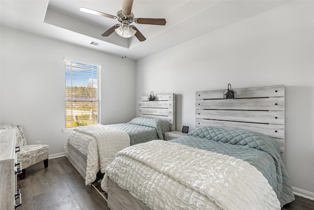 bedroom featuring visible vents, baseboards, a raised ceiling, and dark wood-type flooring