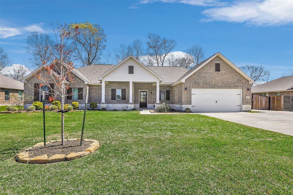 155 Rd 66121, Dayton, TX 77535 - view of front of home featuring brick siding, concrete driveway, a garage, and a front yard