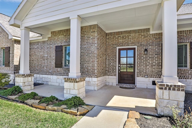 entrance to property with a porch and brick siding