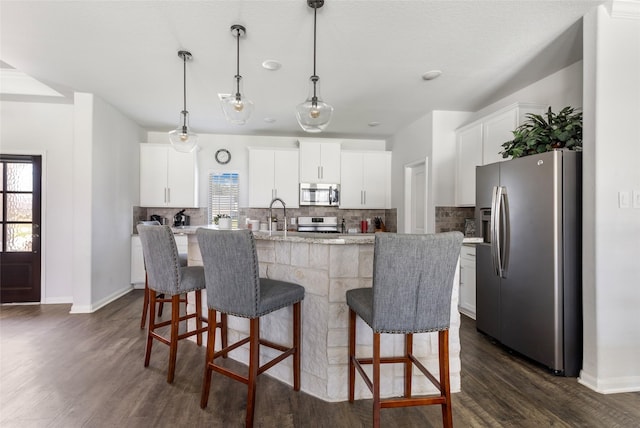 kitchen featuring tasteful backsplash, plenty of natural light, an island with sink, and appliances with stainless steel finishes