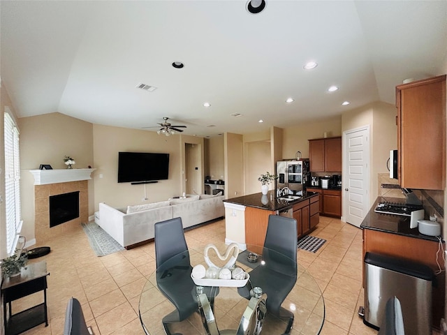 kitchen with dark countertops, visible vents, white microwave, an island with sink, and lofted ceiling