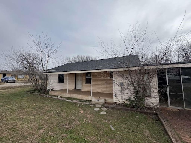 back of house with a yard, covered porch, and roof with shingles