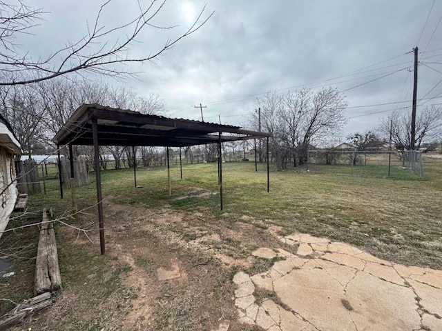 view of yard with a carport, driveway, and fence