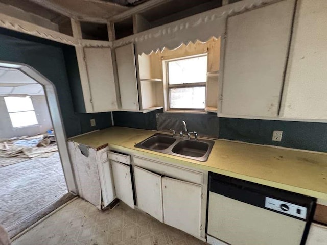 kitchen featuring light countertops, white cabinets, white dishwasher, and a sink