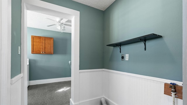 washroom featuring a textured ceiling, carpet, a wainscoted wall, and electric dryer hookup