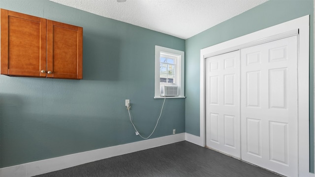 laundry area with cooling unit, dark wood-style floors, baseboards, and a textured ceiling