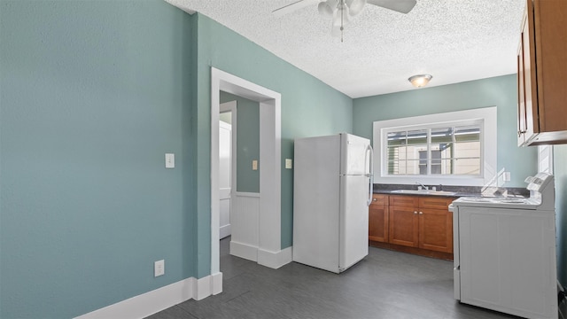 kitchen with brown cabinets, a sink, freestanding refrigerator, stove, and ceiling fan