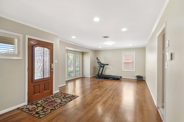 foyer with visible vents, crown molding, baseboards, and wood finished floors