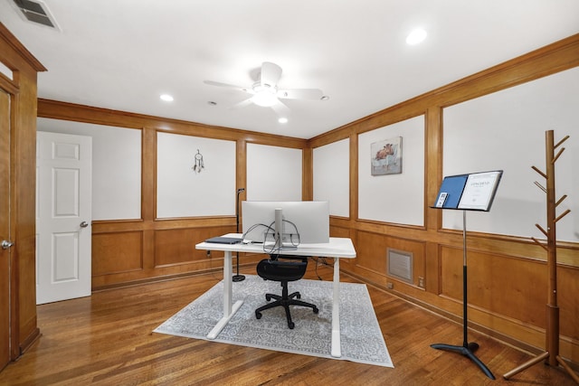 office area with visible vents, a decorative wall, ceiling fan, and wood finished floors