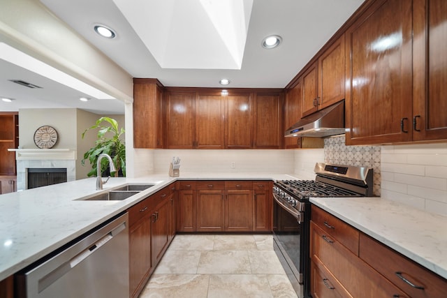 kitchen featuring light stone countertops, visible vents, a sink, appliances with stainless steel finishes, and under cabinet range hood