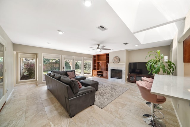 living area featuring visible vents, built in shelves, a premium fireplace, baseboards, and ceiling fan