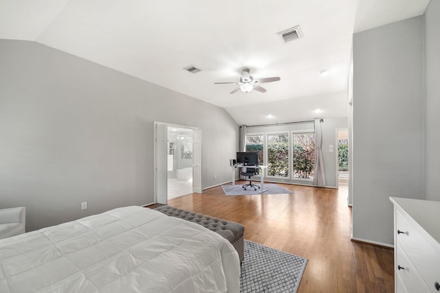 bedroom with vaulted ceiling, wood finished floors, visible vents, and baseboards