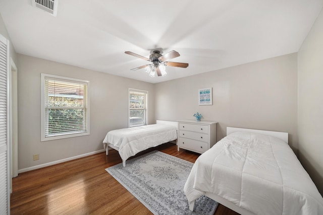 bedroom with multiple windows, wood finished floors, visible vents, and baseboards