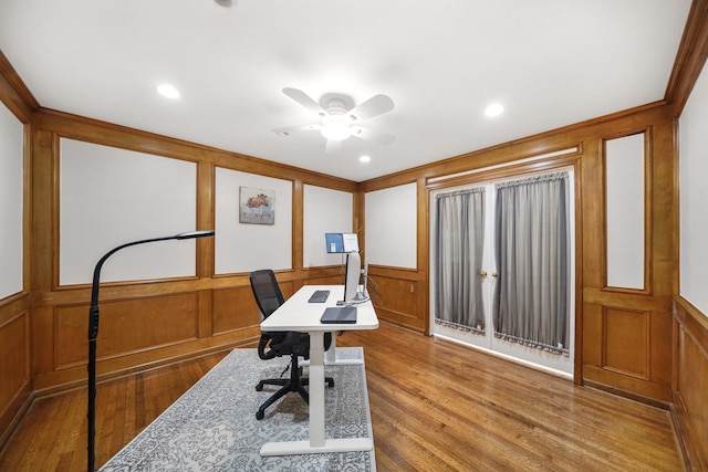 office space featuring ceiling fan, wood finished floors, crown molding, and a decorative wall